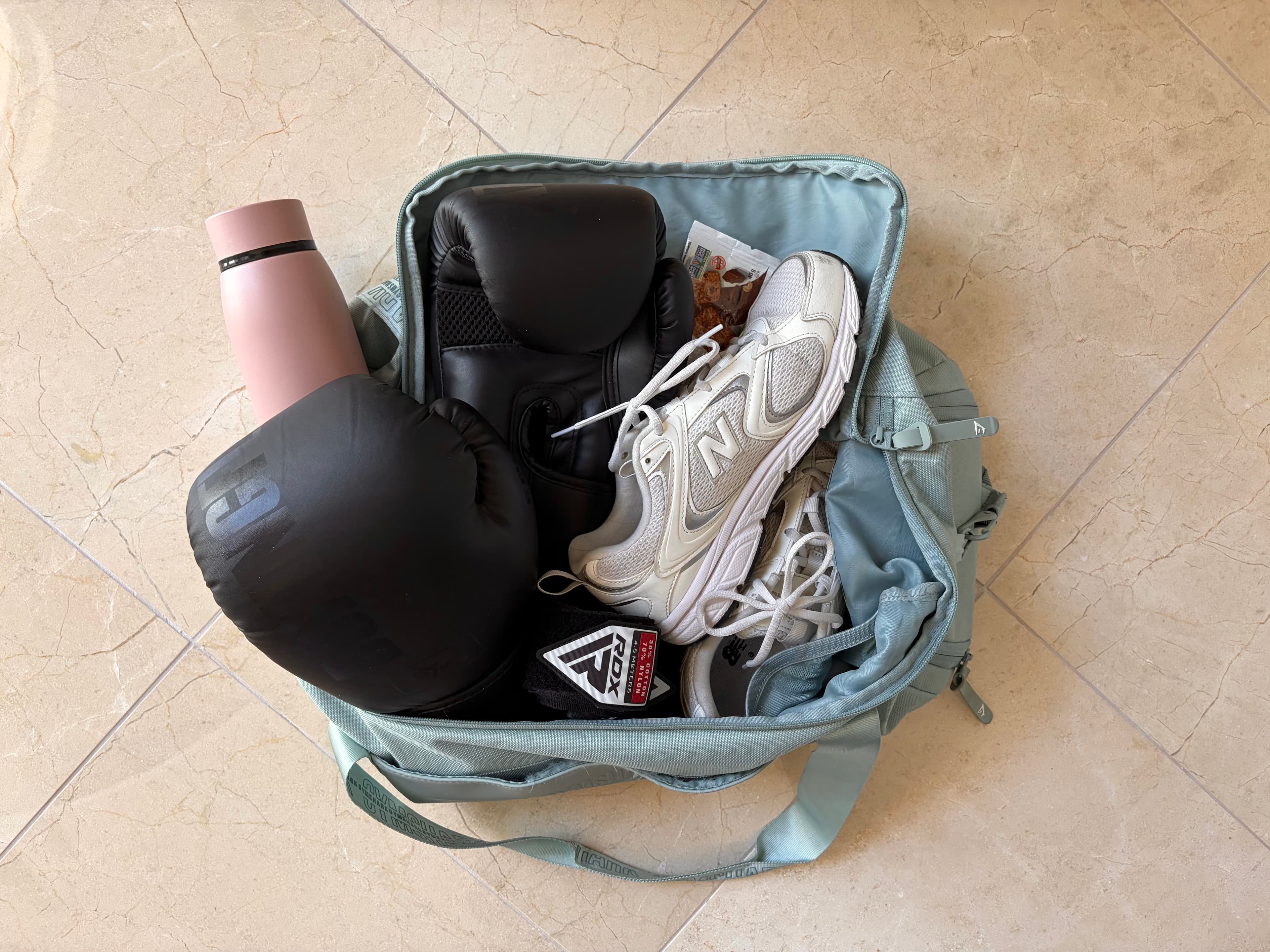 A gym bag packed with boxing gloves and running shoes.